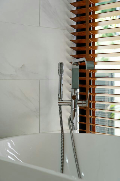 Walk-in shower with handheld fixture and wooden shutter detailing