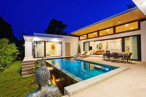 Villa exterior at dusk with illuminated pool, lounge and alfresco dining