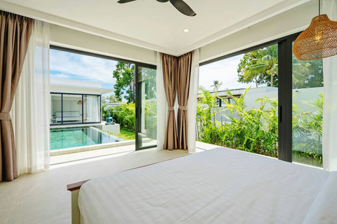 Bright bedroom with sliding doors opening to private pool and tropical garden