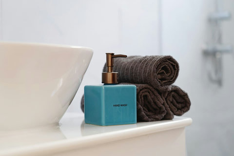 Bathroom detail with folded towels and complimentary soap dispenser