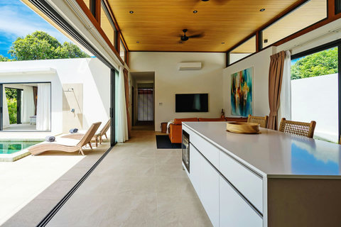 Open-plan living and kitchen with pool views through sliding glass doors