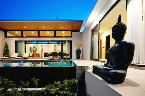 Evening villa view with Buddha statue overlooking the illuminated pool and lounge