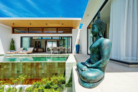 Poolside terrace with Buddha statue, sun loungers and tropical garden views