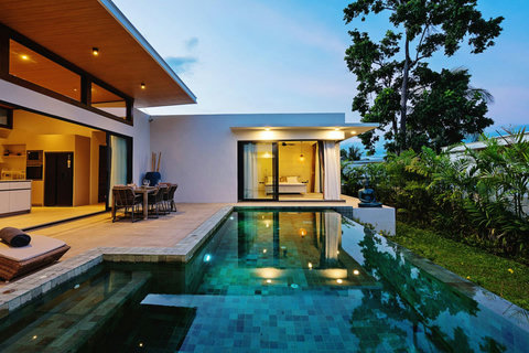 Illuminated infinity pool at dusk - Villa exterior with poolside dining and tropical garden