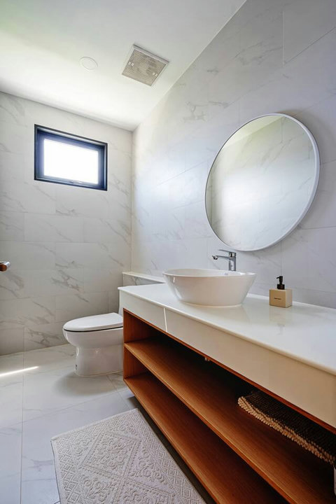 Modern bathroom with round mirror, vessel sink and marble finishes