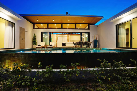 Illuminated villa exterior at night with pool and open-plan living glow