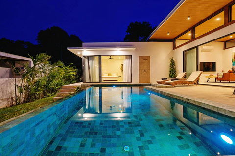 Illuminated infinity pool and villa at dusk with tropical ambiance