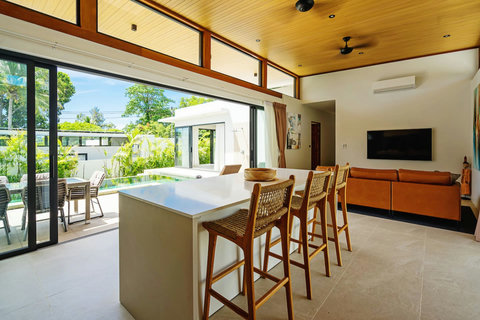 Open-plan living and kitchen with island bar seating and poolside views
