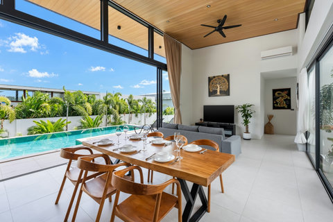 Elegant dining area with teak wood table, perfect for meals with panoramic pool and garden views from the villa