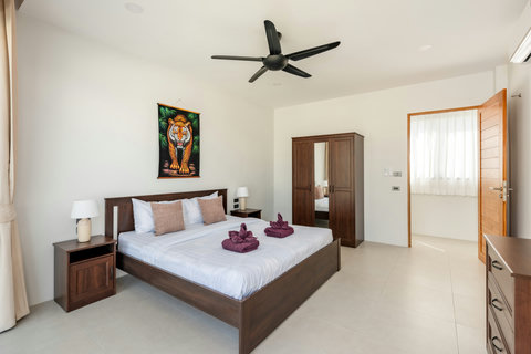 Spacious master bedroom with stunning pool and garden views, premium bedding, and direct access to tropical outdoor spaces