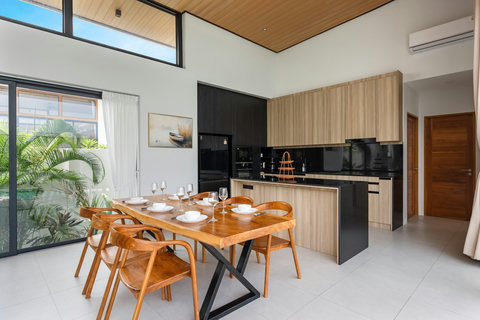 Elegant dining area with teak wood table, perfect for meals with panoramic pool and garden views from the villa