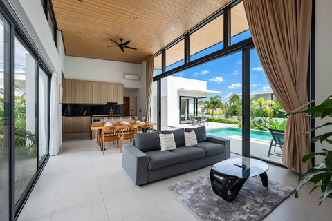 Open-concept living and dining area with floor-to-ceiling windows, modern furnishings, and seamless indoor-outdoor space