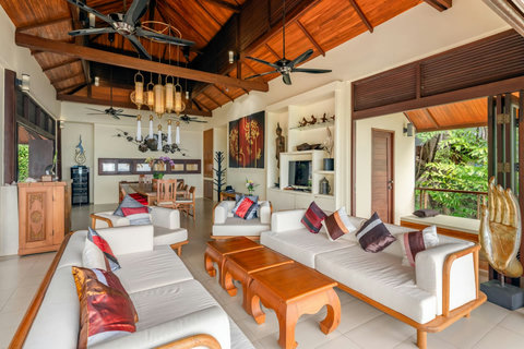 Spacious cottage living area at Bang Kao villa with open-plan kitchen soaring teak ceilings and tropical garden doors