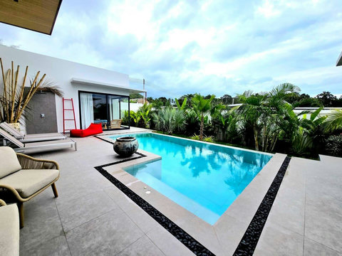 Outdoor pool area with sun loungers and lush tropical garden