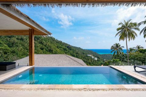 Panoramic pool deck with palm trees and thatched sala overlooking the Gulf of Thailand