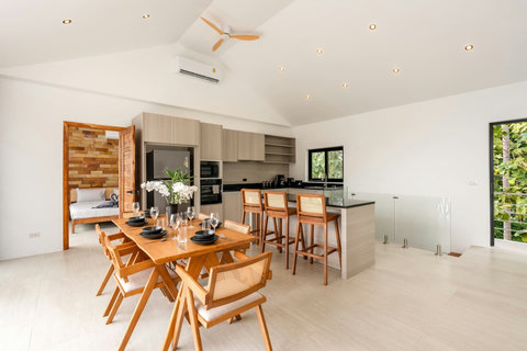 Tropical outdoor dining area with wooden table and pendant lighting at Sunrise Hill Villa