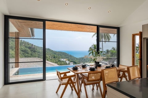 Open-air dining terrace with rattan furniture and sweeping sea views at Koh Samui luxury villa