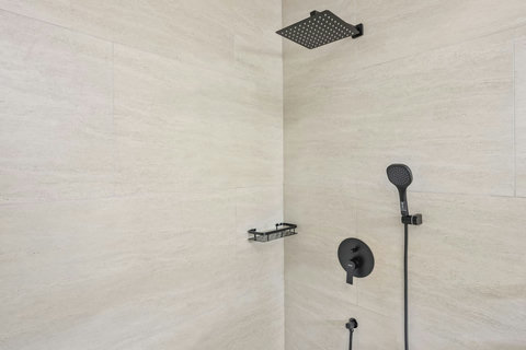 Designer rain shower with matte black fixtures in modern Koh Samui villa bathroom