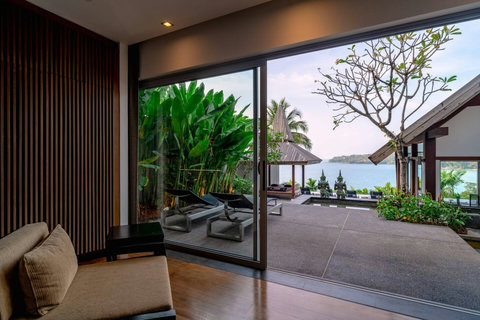 Covered outdoor terrace with sliding glass doors and tropical landscaping at Laemsingh Villa