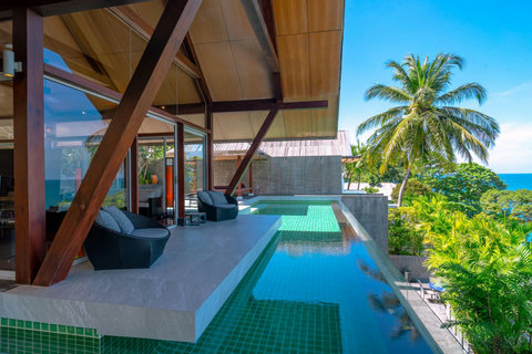Turquoise infinity pool with coconut palms and ocean panorama at Laemsingh Villa, Phuket