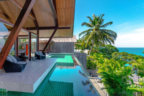 Illuminated infinity pool at twilight with palm trees and ocean views at Laemsingh Villa