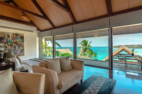 Open-plan living room with floor-to-ceiling views of the pool and sea at Laemsingh Villa