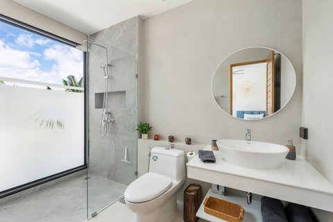 Stylish bathroom with glass rain shower and tropical plants at Villa Solunara, Koh Samui