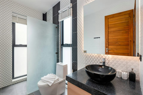Designer bathroom with dark stone vessel sink and natural wood accents at Villa Ombra Koh Samui
