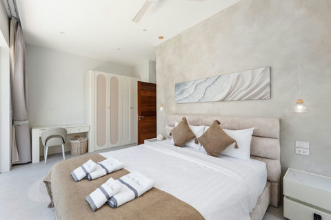 Relax in this calm, minimalist bedroom with warm pendant lighting and soft textures for peaceful sleep.