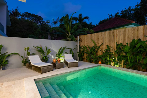 As twilight settles, your private tropical oasis comes alive with soft garden lights, inviting lounge chairs, and the lap of water at your fingertips.