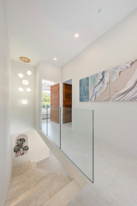 Move through this light-filled corridor with art and soft lighting. The floating stairs feel modern and open, letting light flow freely.