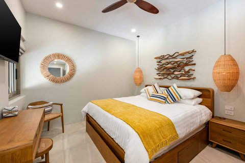 Spacious bedroom with wall TV, vanity desk and rattan accents