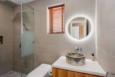 Ensuite bathroom with rain shower and round backlit mirror