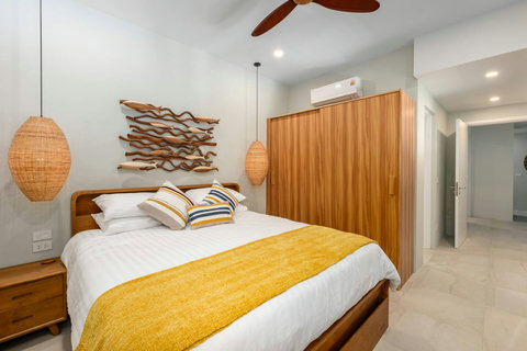 Bedroom with driftwood headboard, rattan pendants and yellow accents