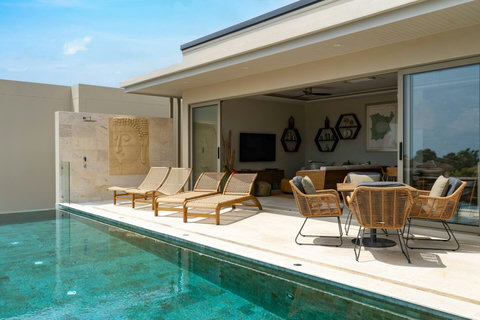 Pool deck with sun loungers and indoor lounge framing the seaview
