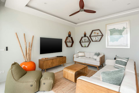 Living room with smart TV, hexagonal shelves and woven décor