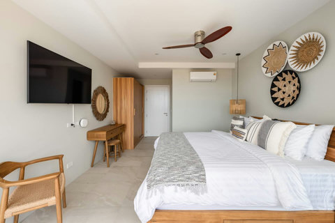 Bedroom with wall-mounted TV, vanity desk and tropical wall décor