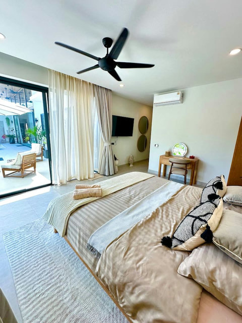 Spacious bedroom with TV, lounge chair and tropical view at Villa Amala 3BR pool villa Koh Samui.