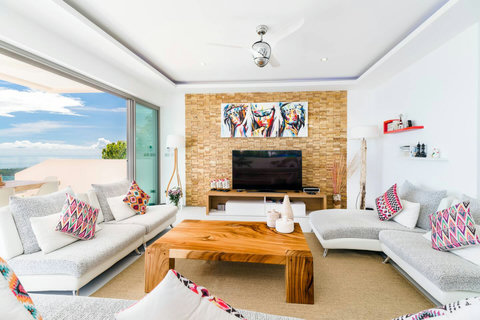 The main lounge area, beautifully blending warm stone-wall textures with modern comfort and a direct view of paradise