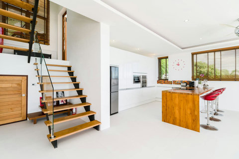 A bright, contemporary entrance showcasing a fully equipped kitchen with sleek wooden accents and stylish breakfast bar
