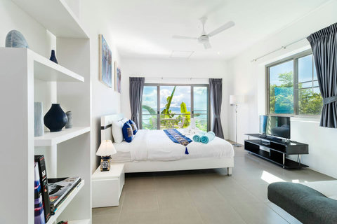 Room N°5 Spacious and sunlit bedroom (Room 5) combining sleek modern comfort with large windows overlooking the lush tropical landscape