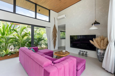 Pink sectional sofa, wall-mounted TV and leafy garden views