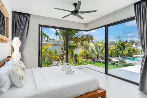 Corner bedroom with garden and pool views through full-height glass doors