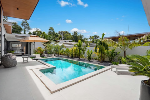Sunny pool terrace with loungers and tropical garden planting
