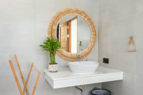 Bathroom vanity with a vessel basin and round woven mirror