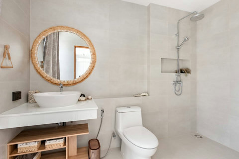 Modern bathroom with a walk-in rain shower and round woven mirror