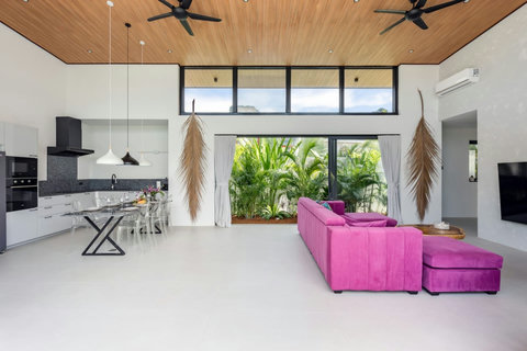 Bright open-plan living room with a pink sofa and high wood ceiling