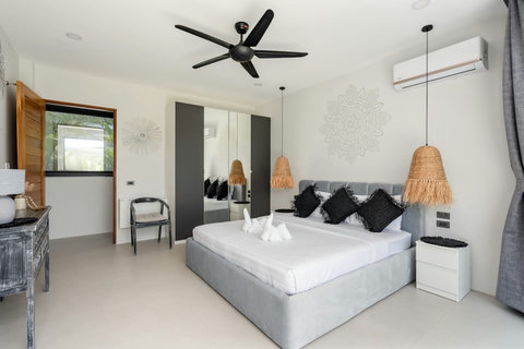Air-conditioned bedroom with a grey upholstered bed and mirrored wardrobe