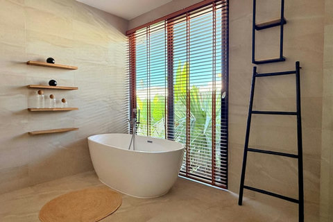 Stylish bathroom with freestanding bathtub and tropical garden views in Koh Samui