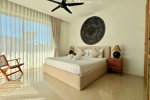 Sunlit master bedroom with floor-to-ceiling windows in a Koh Samui pool villa